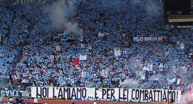 Finalmente è giunto il momento tanto atteso. Lazio - Bayern Monaco illuminerà il manto verde dello Stadio Olimpico di Roma in una serata indimenticabile di Champions League. Nel giorno di San Valentino, i tifosi biancocelesti hanno risposto presente per questa grande occasione degli ottavi di finale. La Curva Nord ha preparato una coreografia speciale per l'evento, progettata con cura e carica di tutta l'emozione che accompagna questo grande match. Attualmente, gli spalti dello Stadio Olimpico ospitano una folla di 59.000 tifosi, secondo quanto riportato dalla nostra redazione, stabilendo così un record stagionale di presenze. La Curva Maestrelli ha esaurito i 1.500 tagliandi messi a disposizione dalla società già ieri, mentre rimangono gli ultimi 3000 biglietti disponibili in Monte Mario. Il pubblico regalerà a Maurizio Sarri una cornice emozionante, carica di senso di appartenenza e voglia di vedere la sua squadra brillare più che mai sotto le stelle della Champions League.