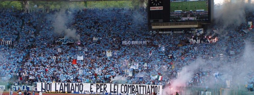Una foto panoramica dello Stadio Olimpico di Roma, con le tribune piene di tifosi della Lazio che sventolano bandiere biancocelesti.