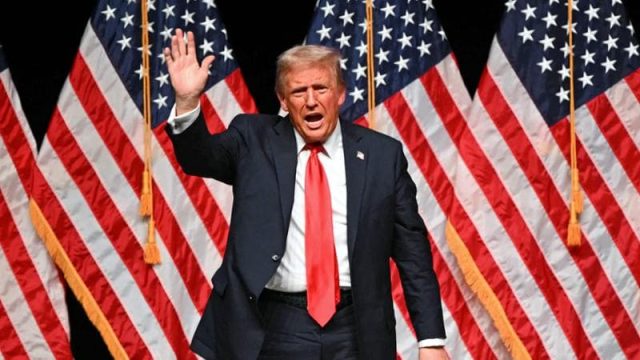 Donald Trump in un evento ufficiale con la bandiera americana sullo sfondo; possibile sede della Supercoppa Italiana a Washington. Donald Trump in un evento ufficiale con la bandiera americana sullo sfondo; possibile sede della Supercoppa Italiana a Washington.