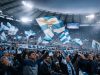 Lazio, il sogno arabo svanisce: il caso Guido Reni e le illusioni dei tifosi Tifosi della Lazio allo stadio, con bandiere e sciarpe, in uno stato d’animo tra speranza e delusione.