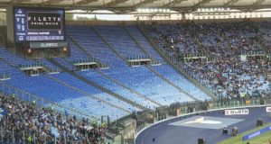 🎟️ Coppa Italia, Lazio-Milan: Scatta la Vendita dei Biglietti. Info, Prezzi e Abbonati Grafica informativa con un biglietto digitale della Lazio per la Coppa Italia e lo sfondo dello Stadio Olimpico illuminato.