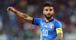 Lorenzo Insigne parla di Napoli, Sarri e futuro in Italia Lorenzo Insigne sorridente in abiti civili, immaginato nel contesto romano in attesa della firma con la Lazio.