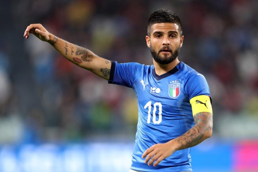 Lorenzo Insigne sorridente in abiti civili, immaginato nel contesto romano in attesa della firma con la Lazio.