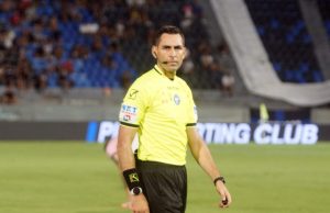 Lazio scrive alla Lega: “Serve chiarezza sugli arbitri” L'arbitro Colombo con un'espressione preoccupata durante una partita, con i loghi dei principali quotidiani sportivi italiani sullo sfondo.