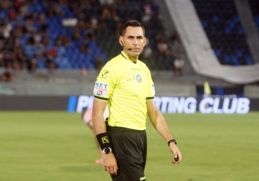 L'arbitro Colombo con un'espressione preoccupata durante una partita, con i loghi dei principali quotidiani sportivi italiani sullo sfondo.